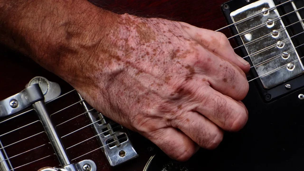 musician’s hand on a guitar musician’s hand on a guitar